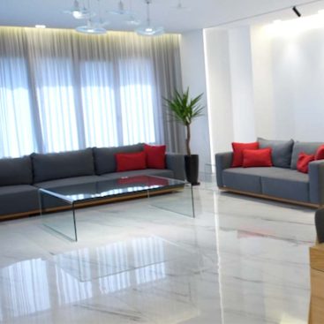 An elegant living room with grey couches and bright red pillows, offering a warm and welcoming environment for relaxation.